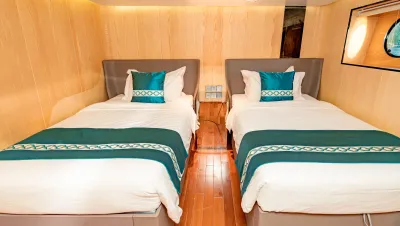 Deluxe Twin cabin on Black Pearl — two single beds with turquoise linen