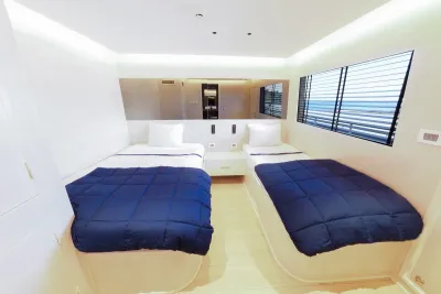 Upper-deck cabin on Blue Force Three — two beds and a window with an ocean view