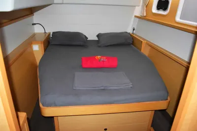 Double cabin on Gros Plan — double bed, light wood joinery and a towel with the dive centre logo