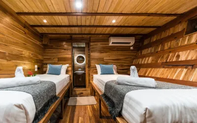 Deluxe cabin on Komodo Aggressor — two single beds along the timber sides with a porthole between them