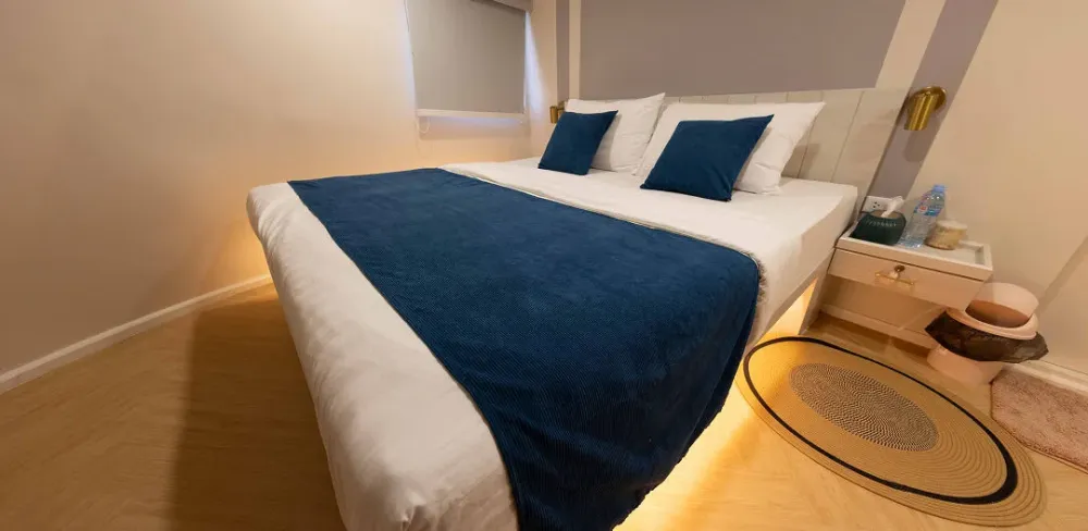 Double bed in the Krishna 3 master cabin with a blue throw and bedside table