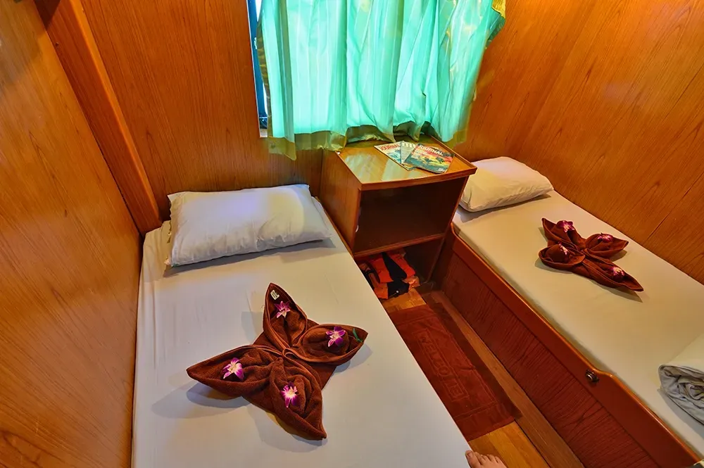 Twin cabin on Manta Queen 2 with wood panelling and towels laid out
