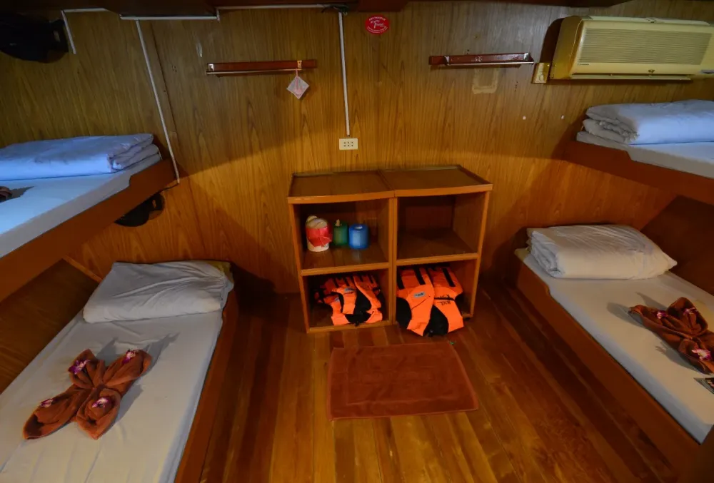 Four-berth cabin on Manta Queen 2 with a wooden floor and life jackets on the shelves