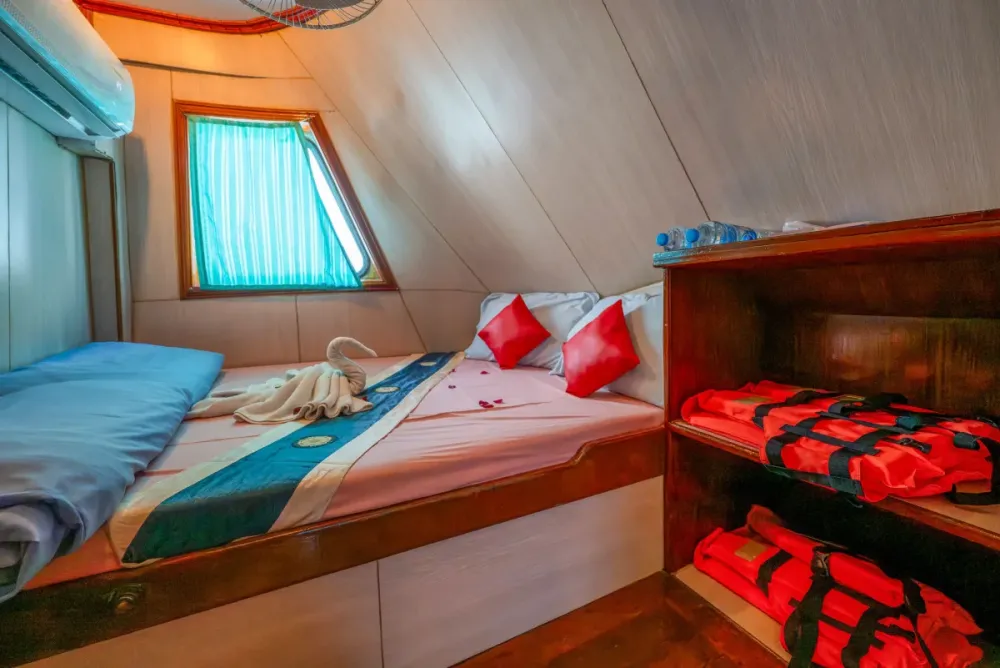 Double cabin on Manta Queen 2 — double bed beside a curtained window