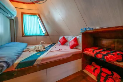 Double cabin on Manta Queen 2 — double bed beside a curtained window