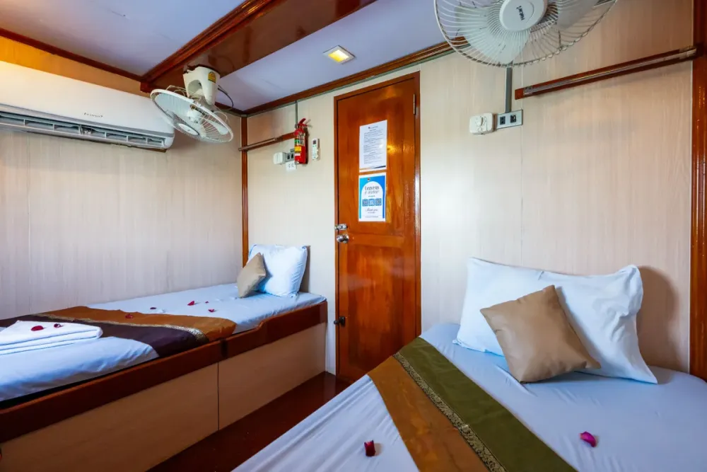 Bright twin cabin on Manta Queen 2 with fans and storage shelves