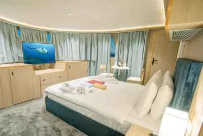 Balcony Suite на Philippines Aggressor II — кровать king, шторы во всю стену и монитор напротив