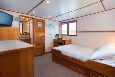 Upper deck suite on Sea Hunter — bed, TV and the bathroom door