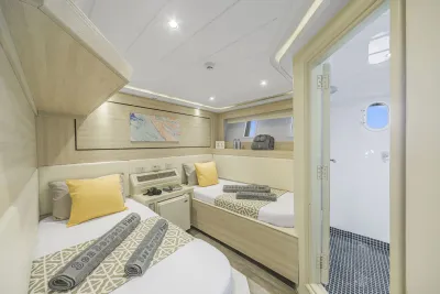 Каюта Standard Twin на нижней палубе Sea Serpent Grand — две кровати и открытая дверь в санузел с иллюминатором