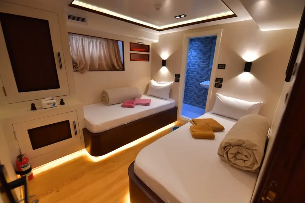 Lower deck twin cabin on South Moon 1 — two beds, curtained window and the bathroom door