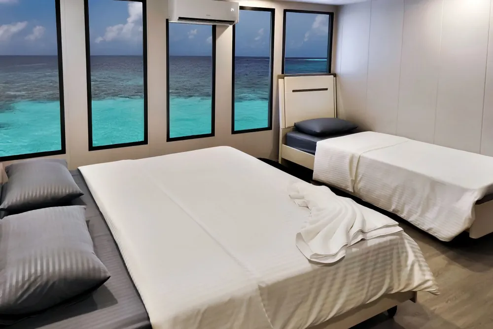 Upper deck suite on Spirit of Maldives — panoramic windows over the turquoise lagoon
