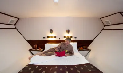 Lower-deck master stateroom on Thailand Aggressor — queen bed under a sloping deckhead