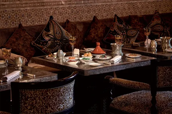 La Grande Table Marocaine — стол с тажином в зале с резными подушками и серебряной посудой