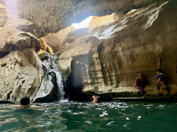 Grotto — waterfall pouring through a hole in the ceiling, people swimming below