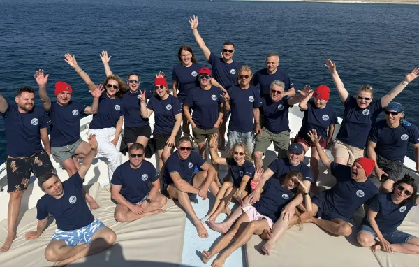 Group photo on the yacht deck — everyone in matching blue shirts