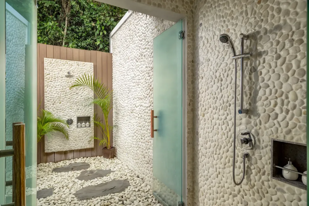Open-air villa shower with pebble walls
