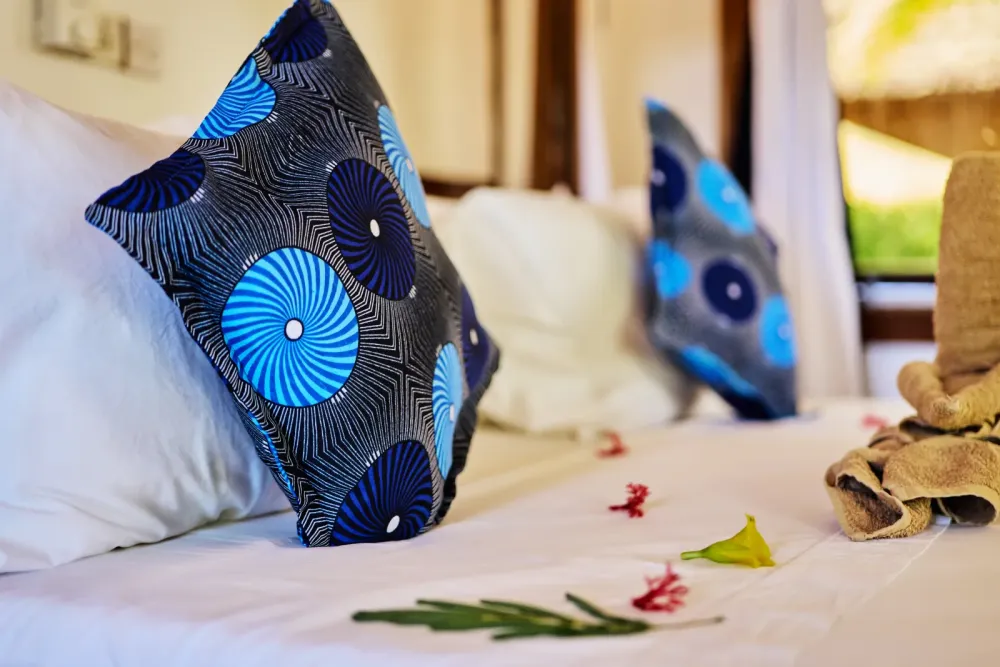 Подушки с местным узором и цветы на застеленной кровати