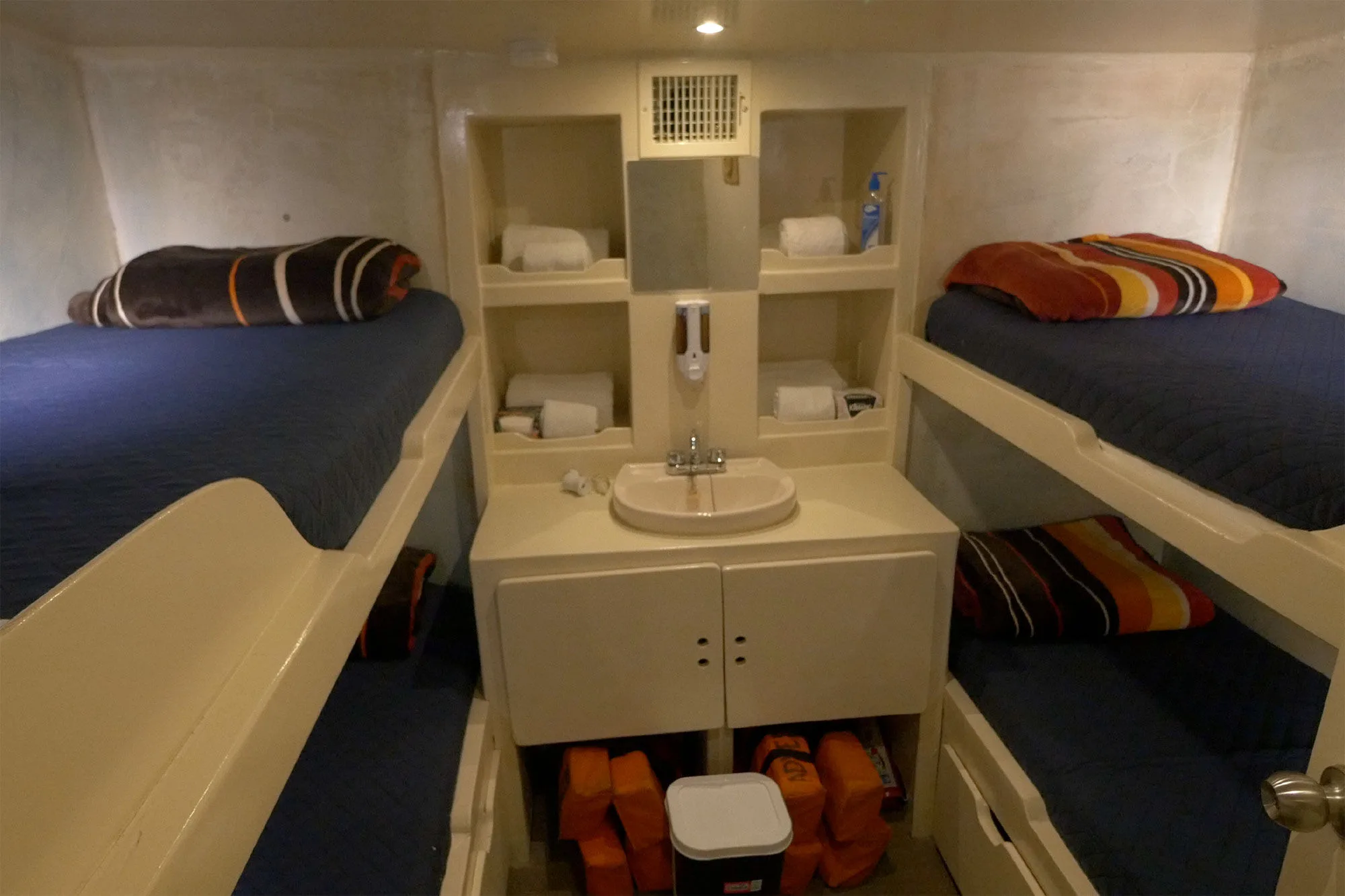 Quad cabin aboard Adventure with two sets of bunk berths and a washbasin between them