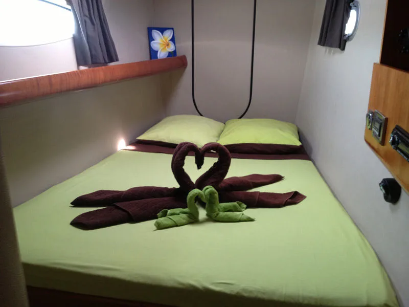 The same cabin in daylight, towels folded into a heart and a flower on the bulkhead