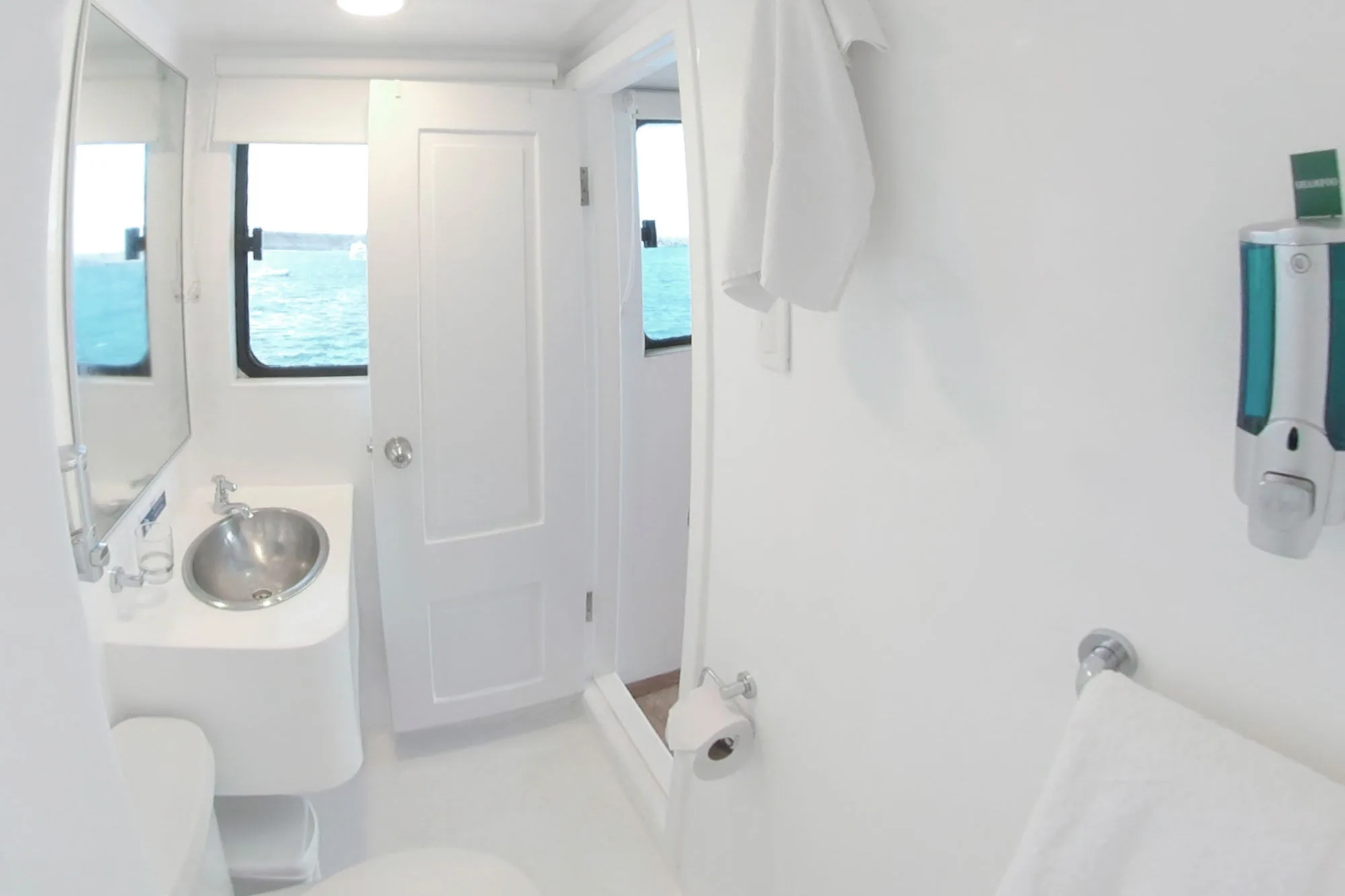 Aqua bathroom with a window looking out to sea