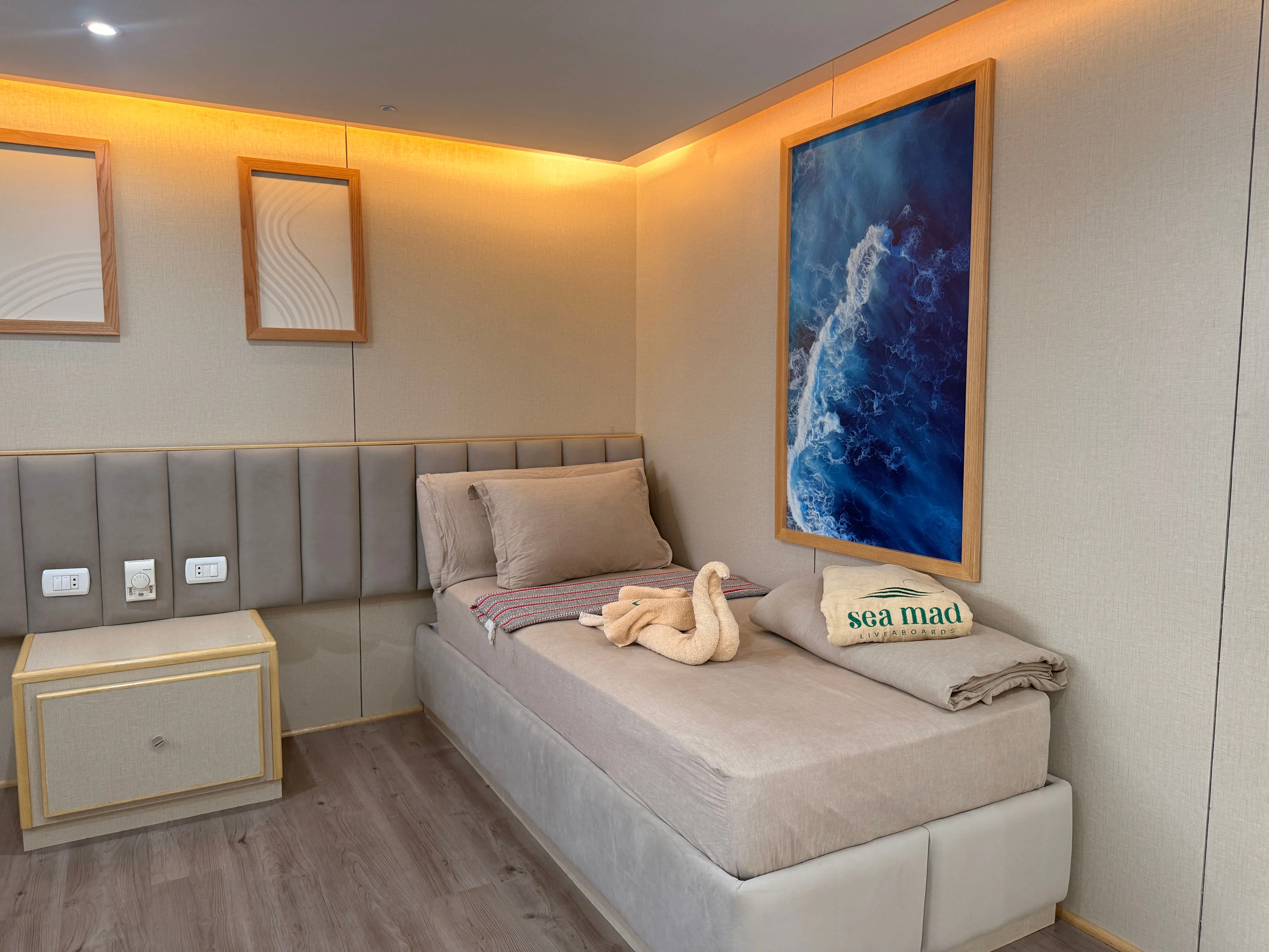 Standard cabin on Avo — bed, cabinet and artwork on the bulkhead