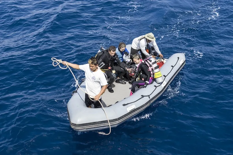 A group of divers heading out on a dinghy
