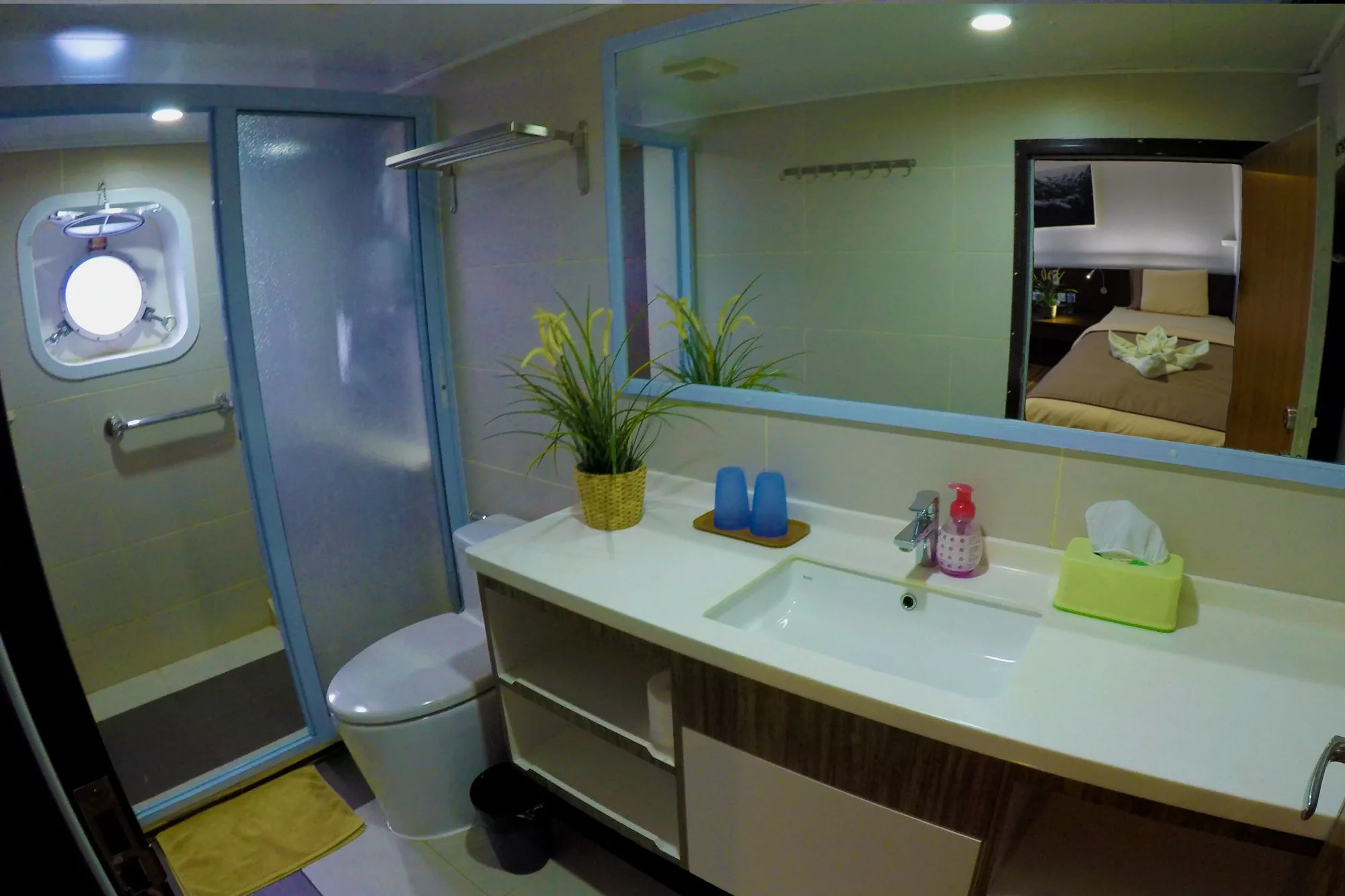 Lower deck bathroom — shower, toilet and basin, with a porthole in the shower door