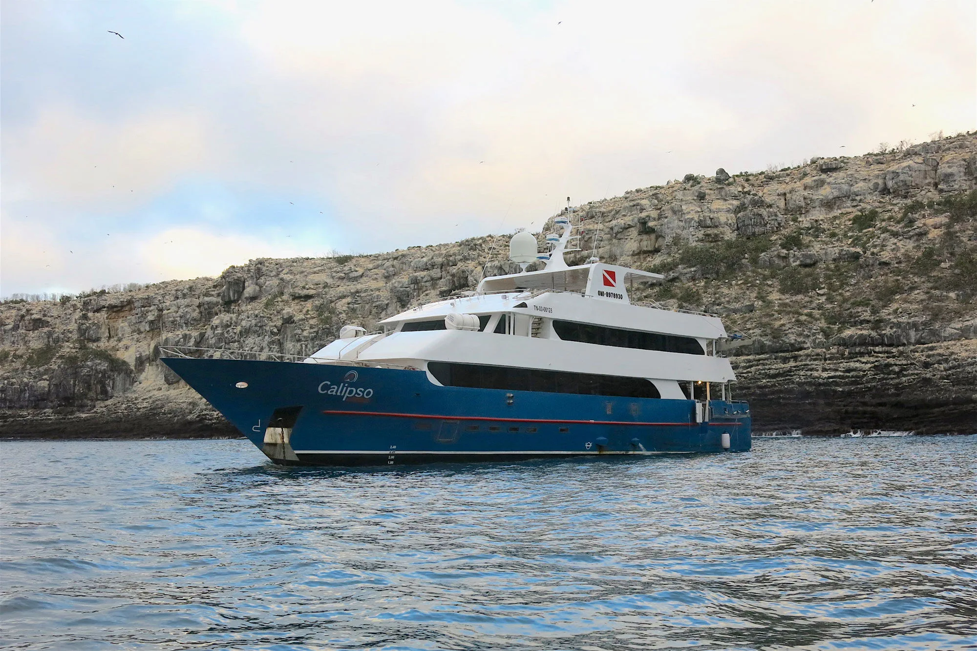 Calipso beside the rocky shore of a Galapagos island