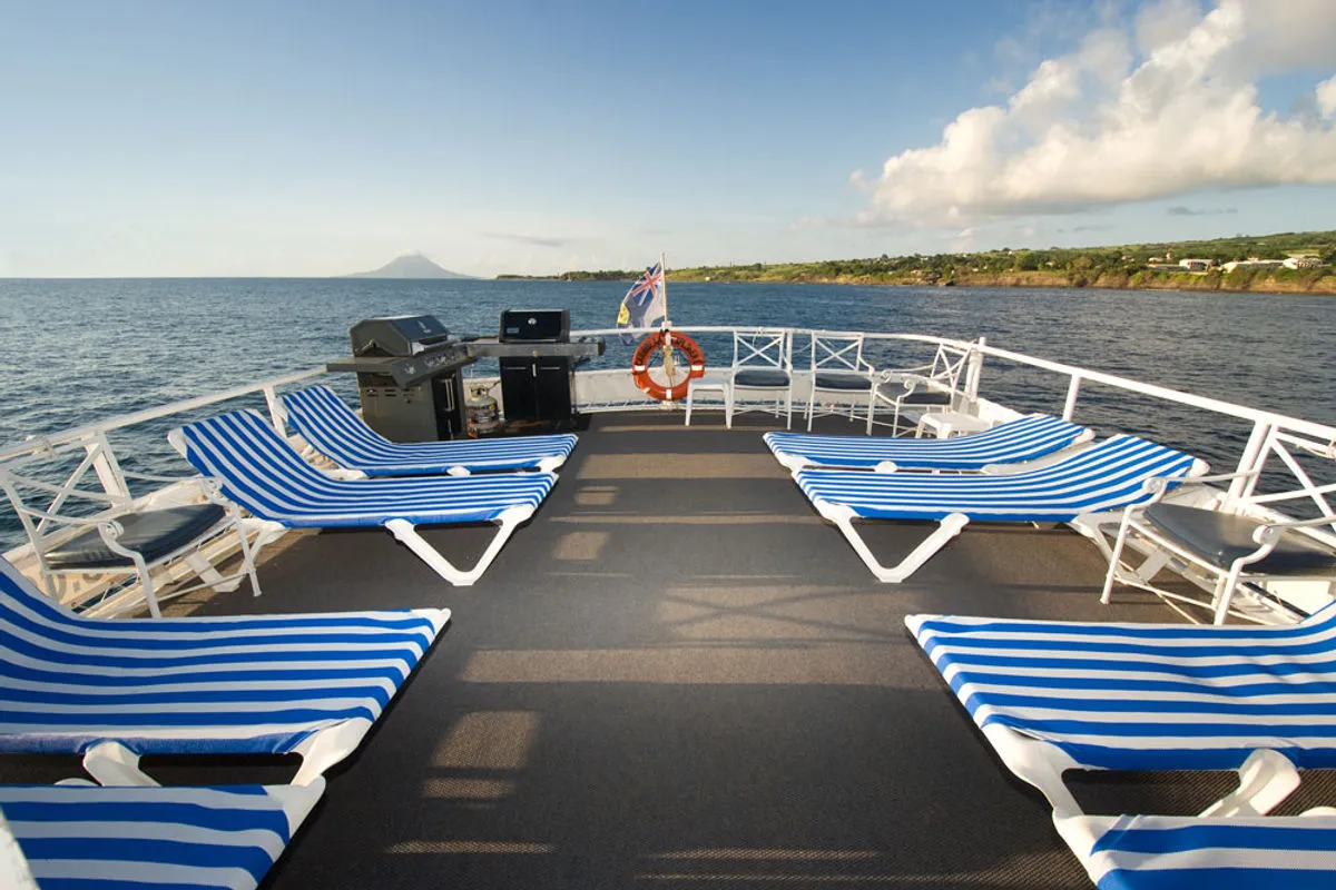 Солнечный дек Caribbean Explorer II с шезлонгами и видом на вулкан Сабы