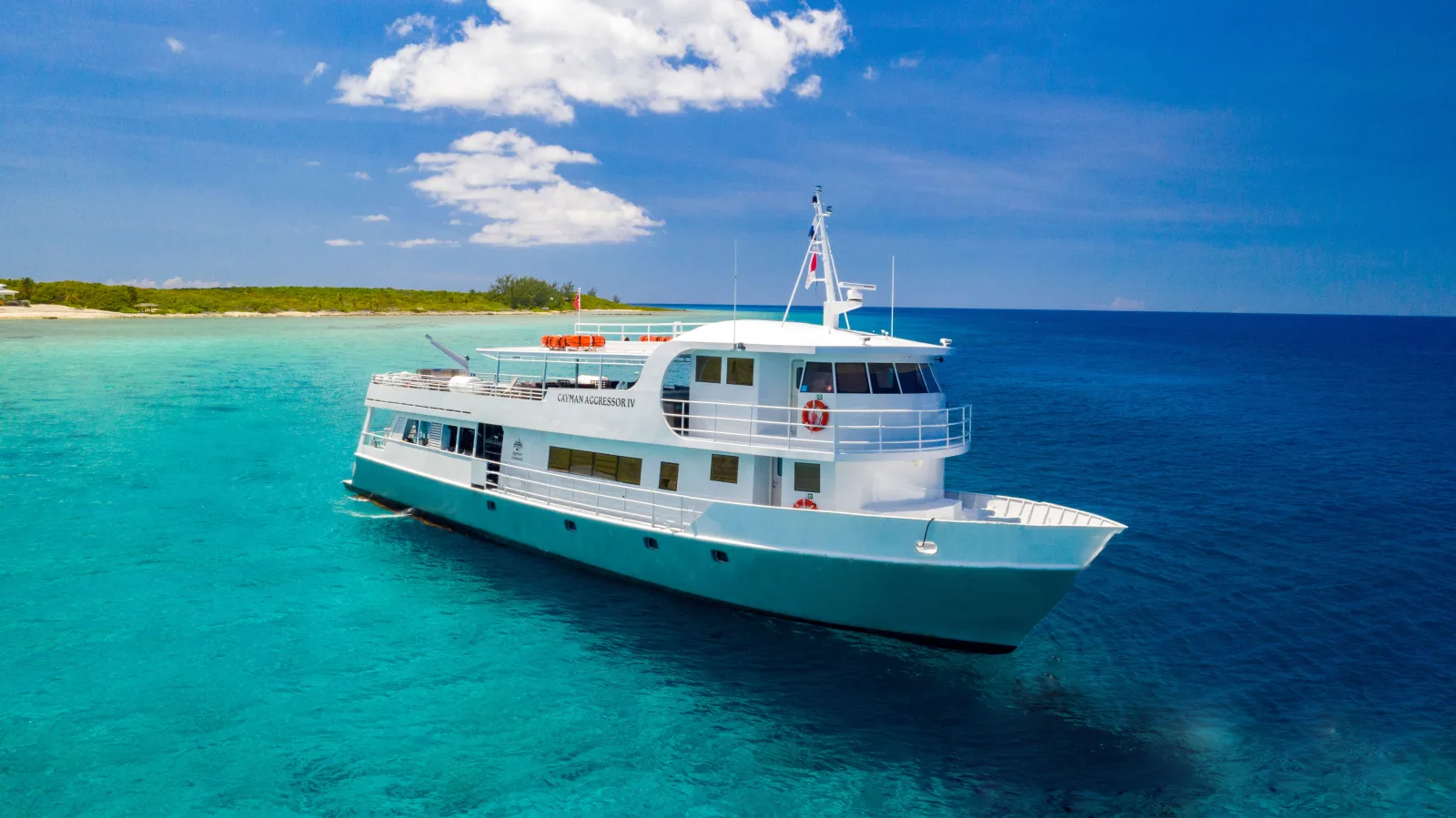 Cayman Aggressor IV anchored off a sandy Cayman shoreline