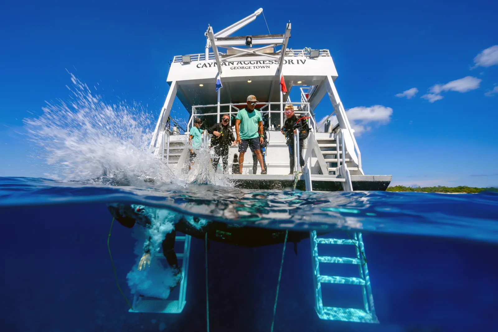 Divers entering the water from the stern platform of Cayman Aggressor IV