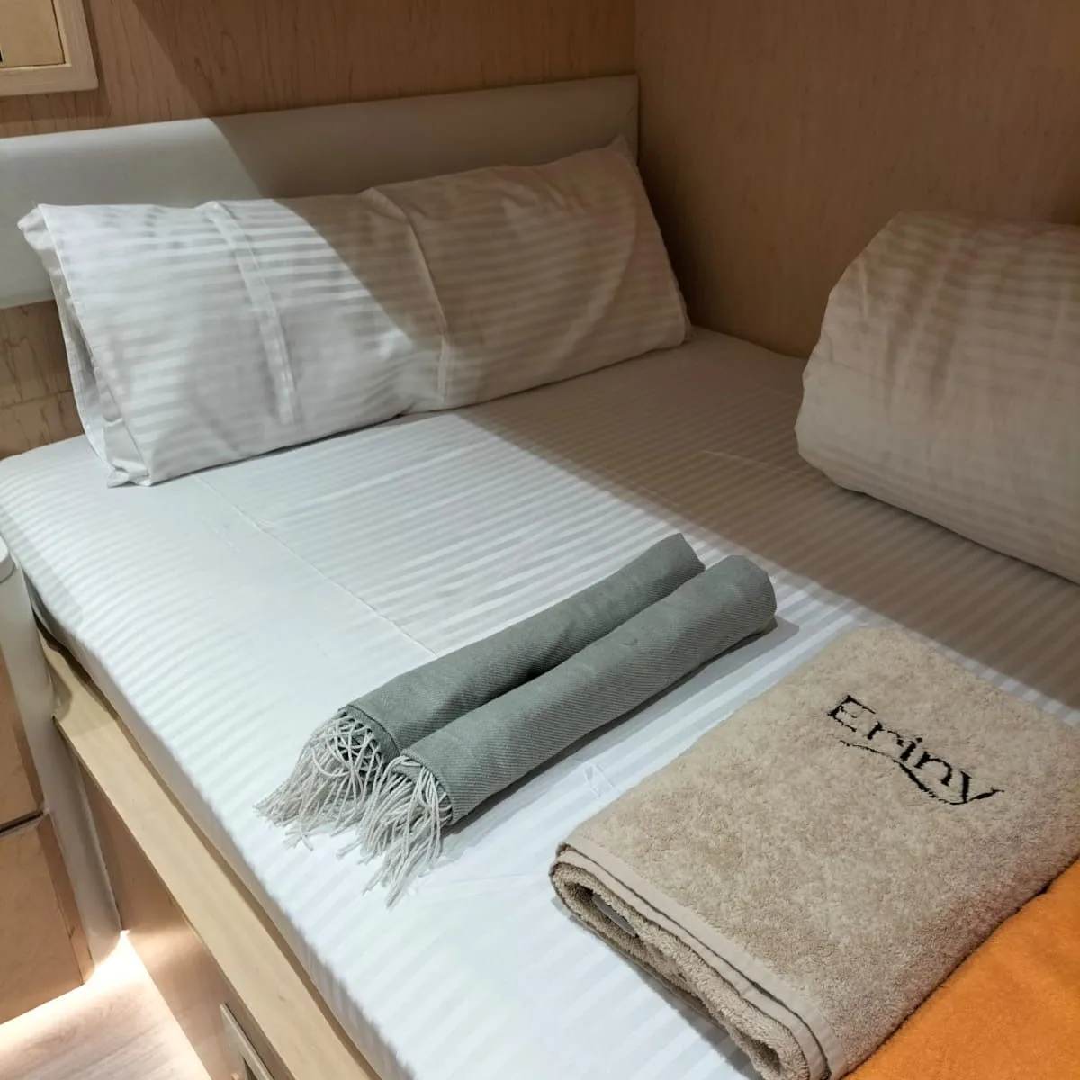 Made-up lower berth of a bunk cabin on Eriny with a branded towel