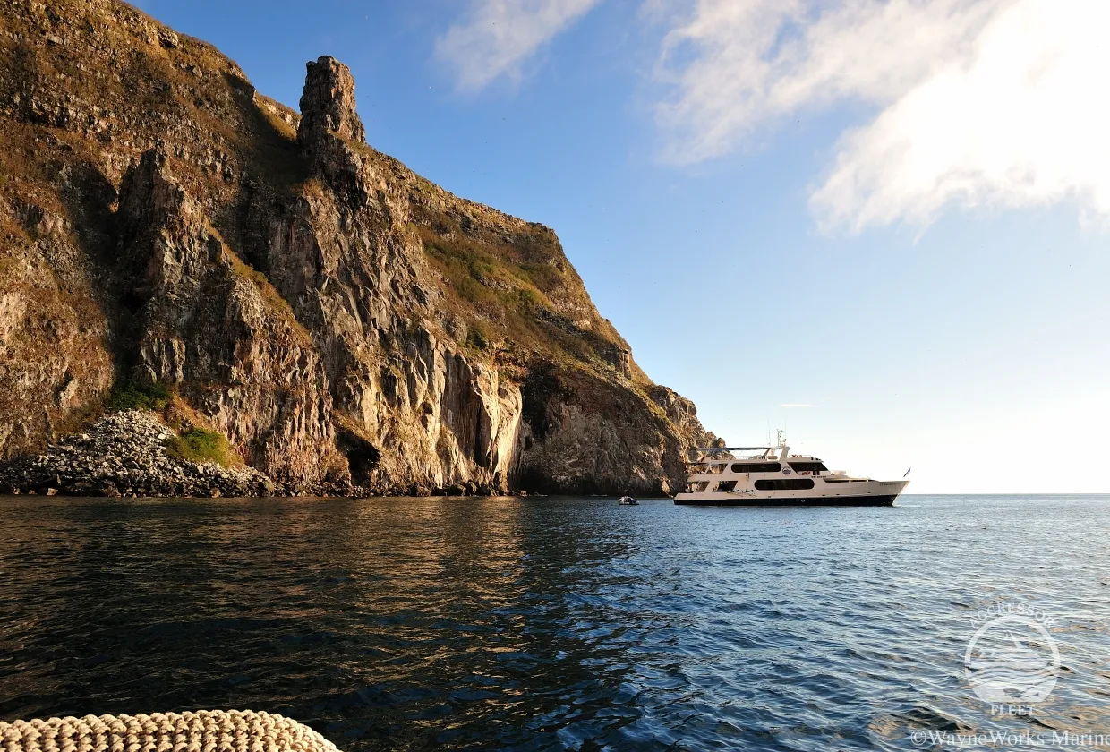 Galapagos Aggressor III off a rocky coast at sunset