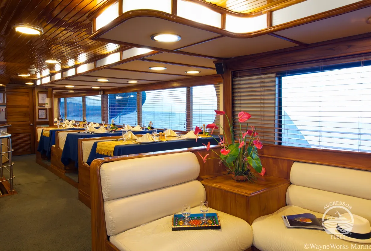 Dining area of Galapagos Aggressor III with sofas and picture windows