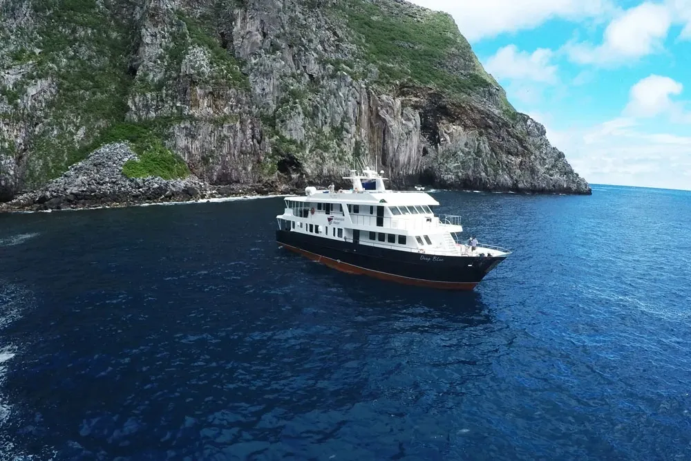 Galapagos Master anchored under a sheer island wall