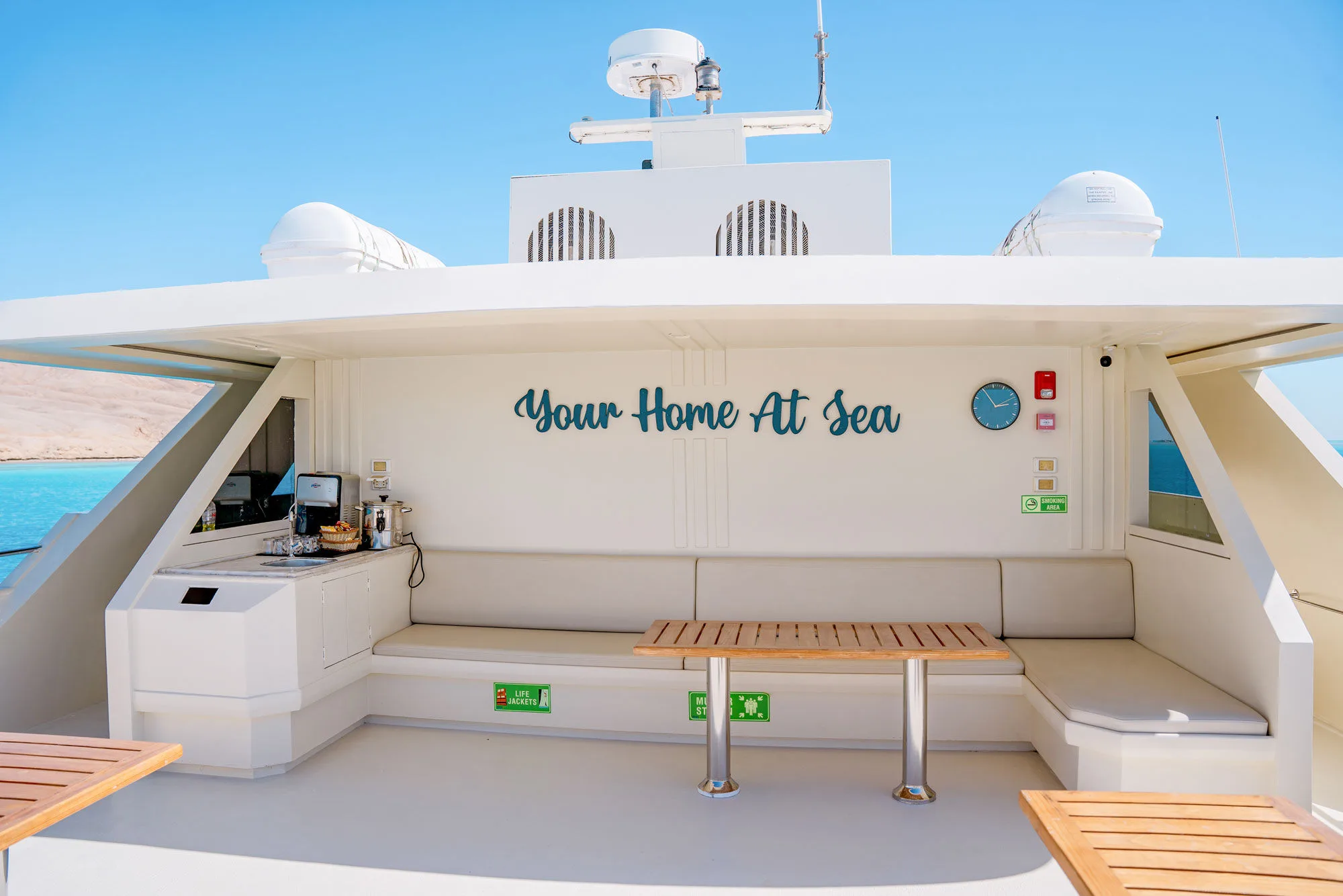 Открытая лаунж-зона с надписью Your Home At Sea и барной стойкой