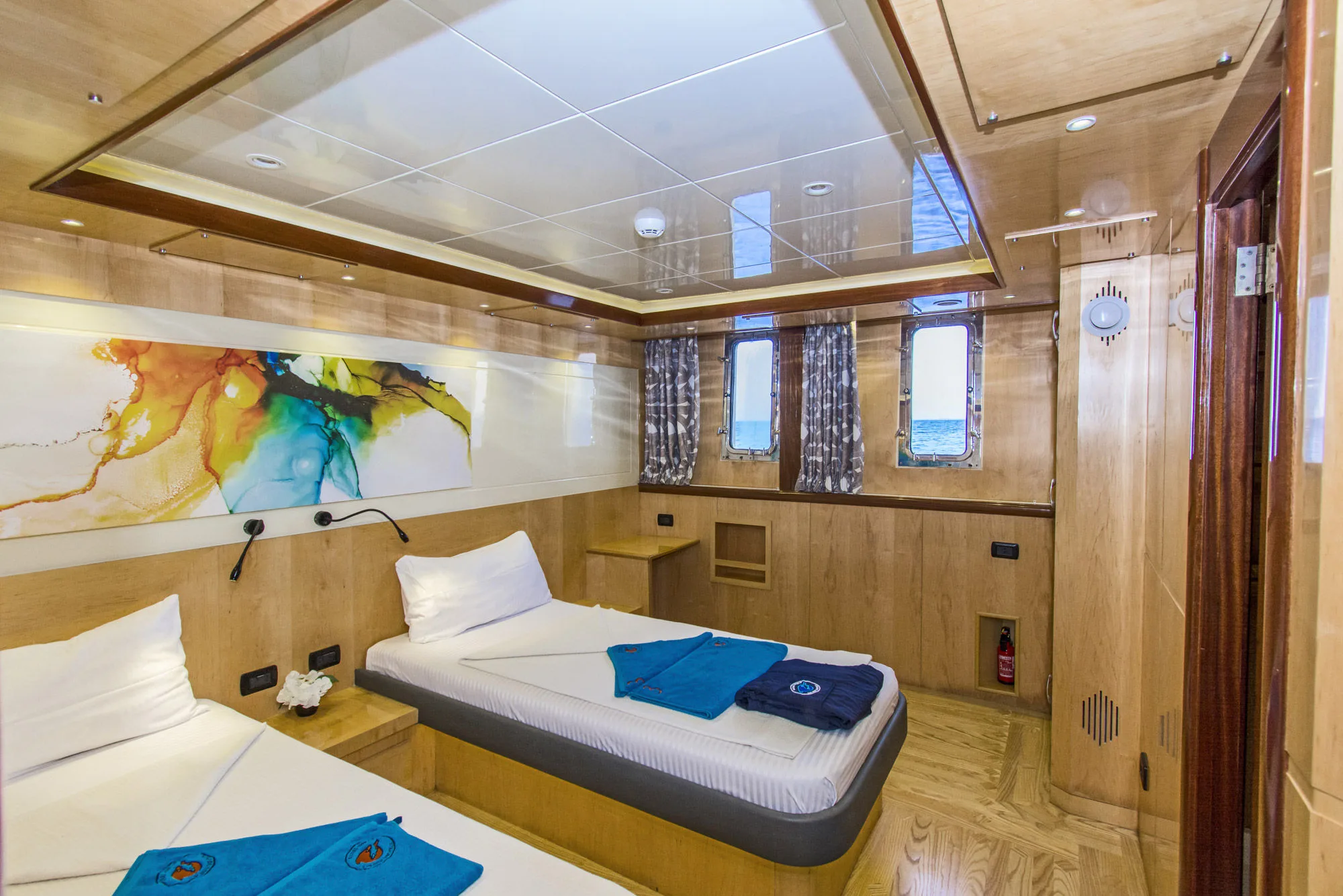 Каюта нижней палубы Golden Dolphin IV — тумбы между кроватями и иллюминатор