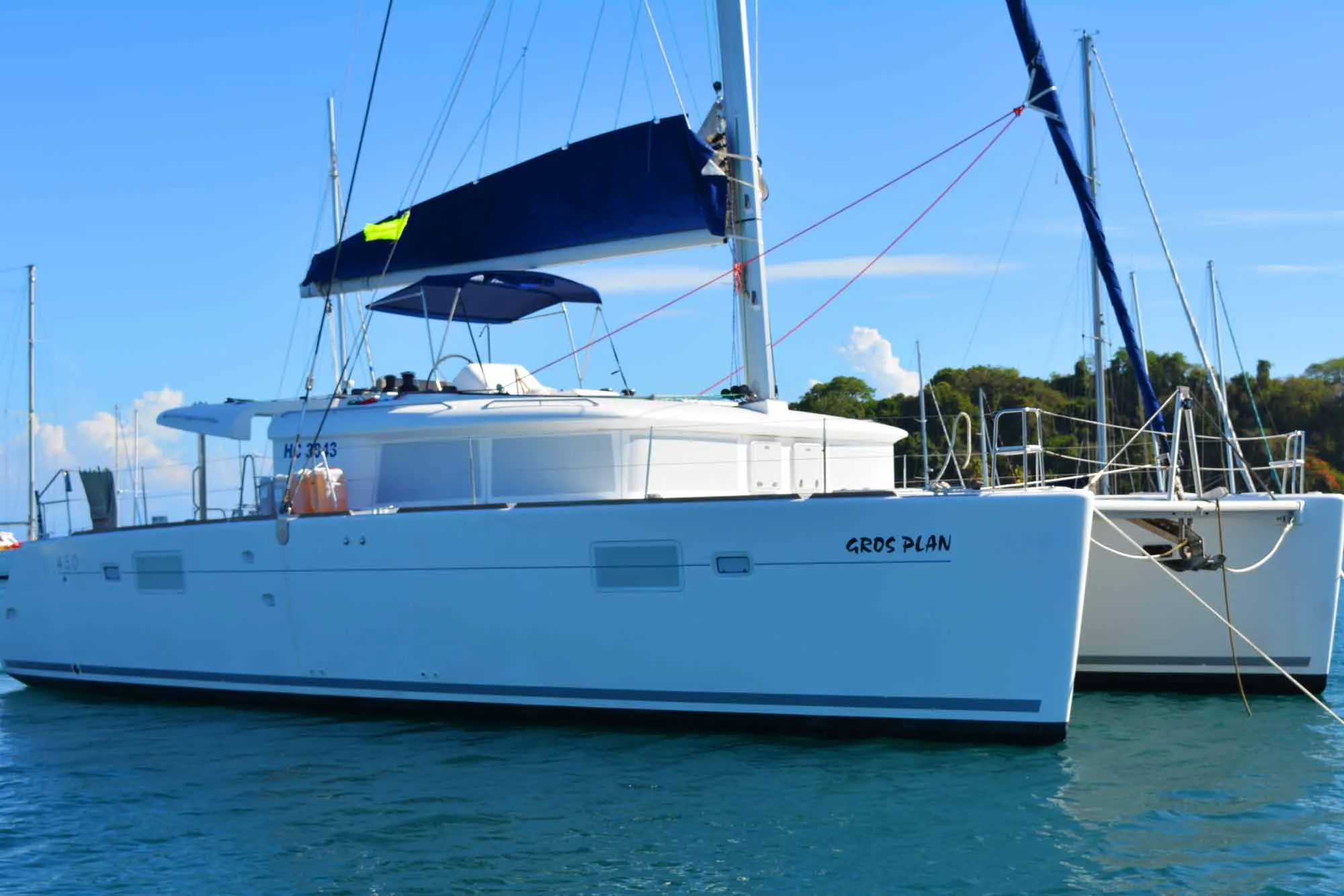 The catamaran Gros Plan at anchor, her name on the hull