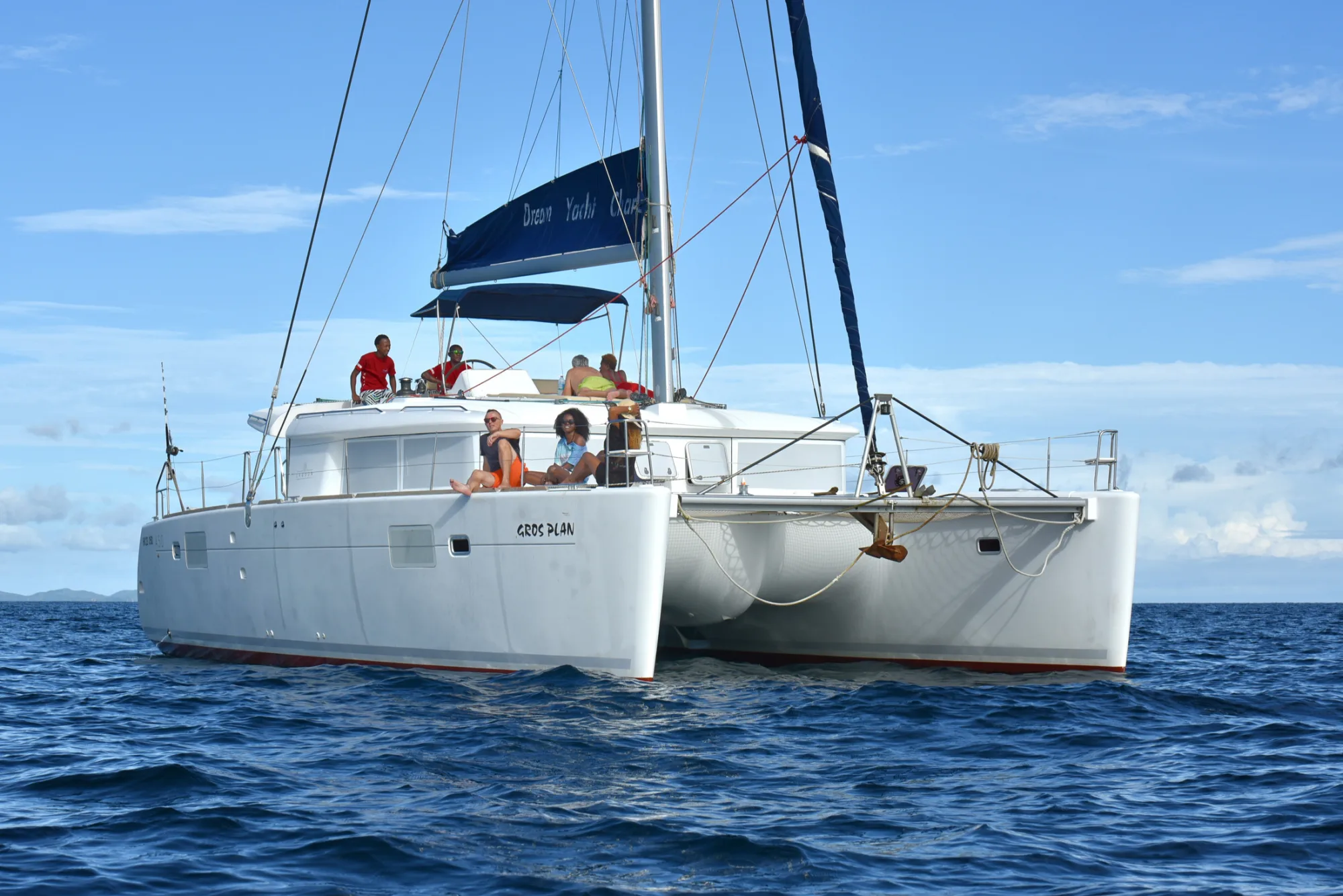 Guests on the deck of Gros Plan off a green island