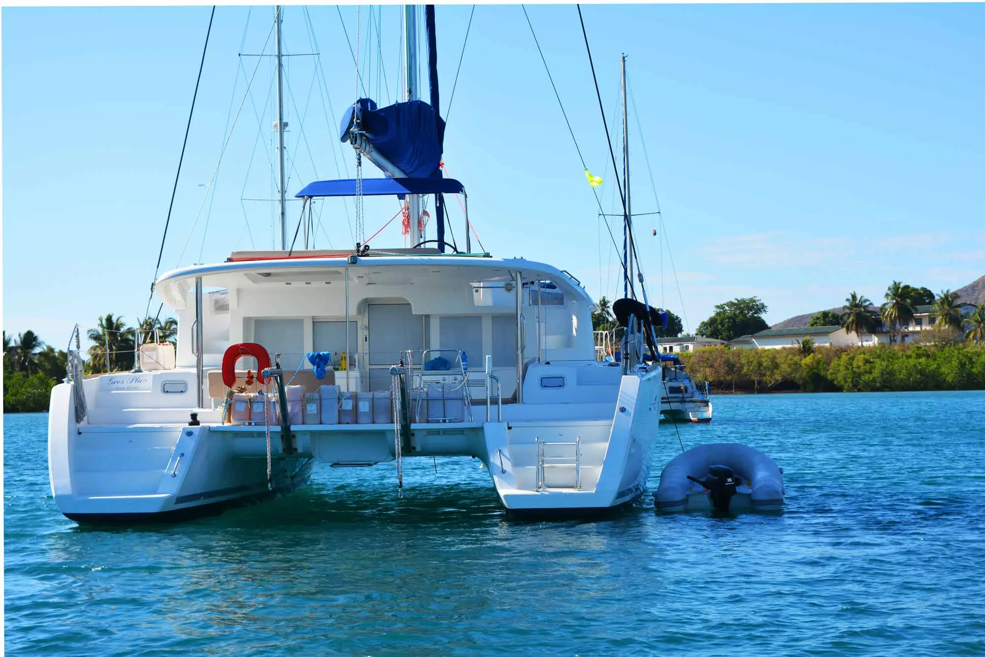 The stern of the catamaran with her tender at an anchorage