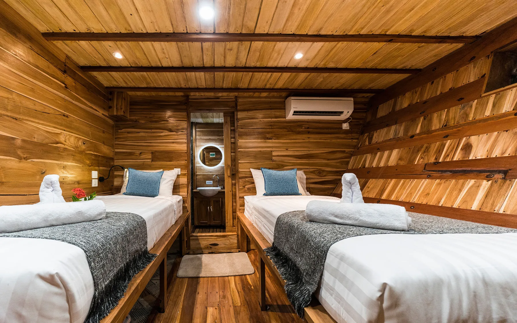 Deluxe cabin on Komodo Aggressor — two single beds along the timber sides with a porthole between them