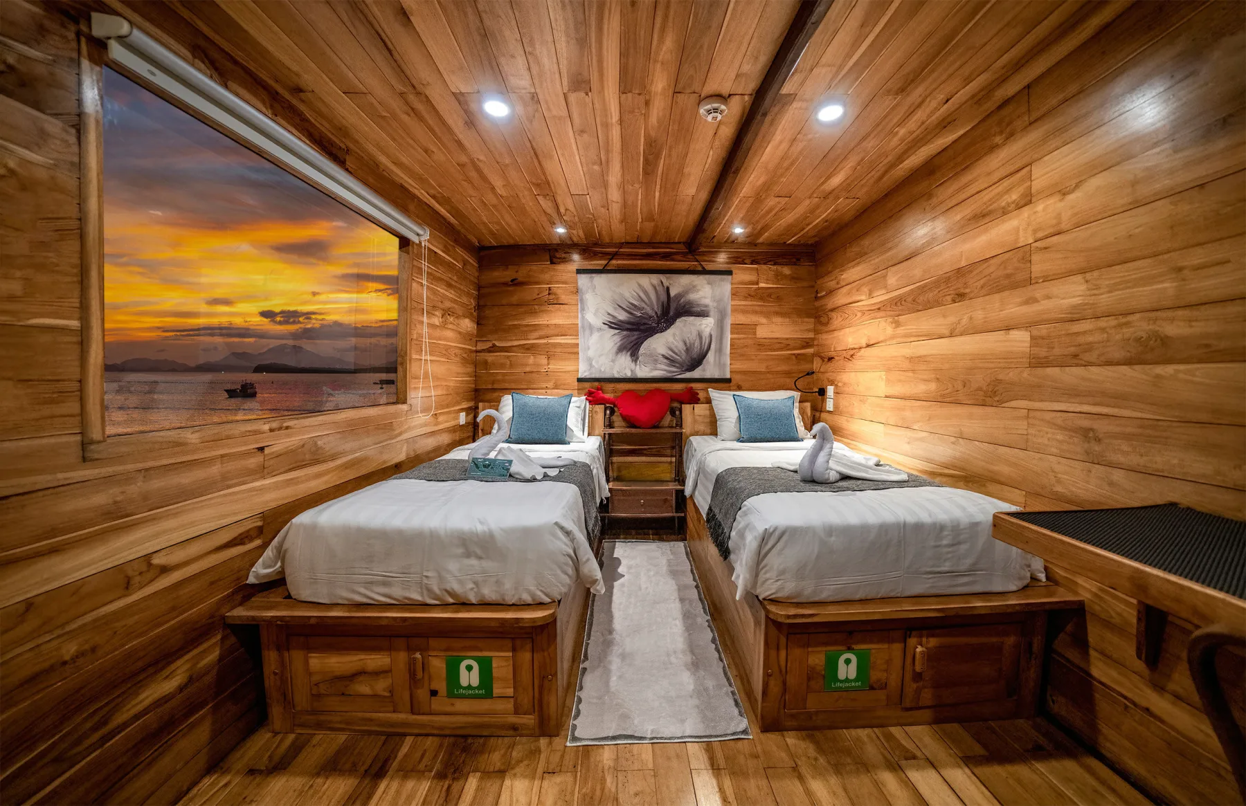 Master Stateroom on Komodo Aggressor — picture window with sunset over the islands and two single beds