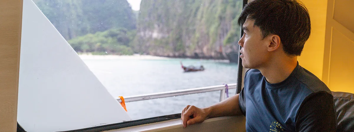 A guest on Krishna 3 watching the Phi Phi limestone cliffs from the saloon window