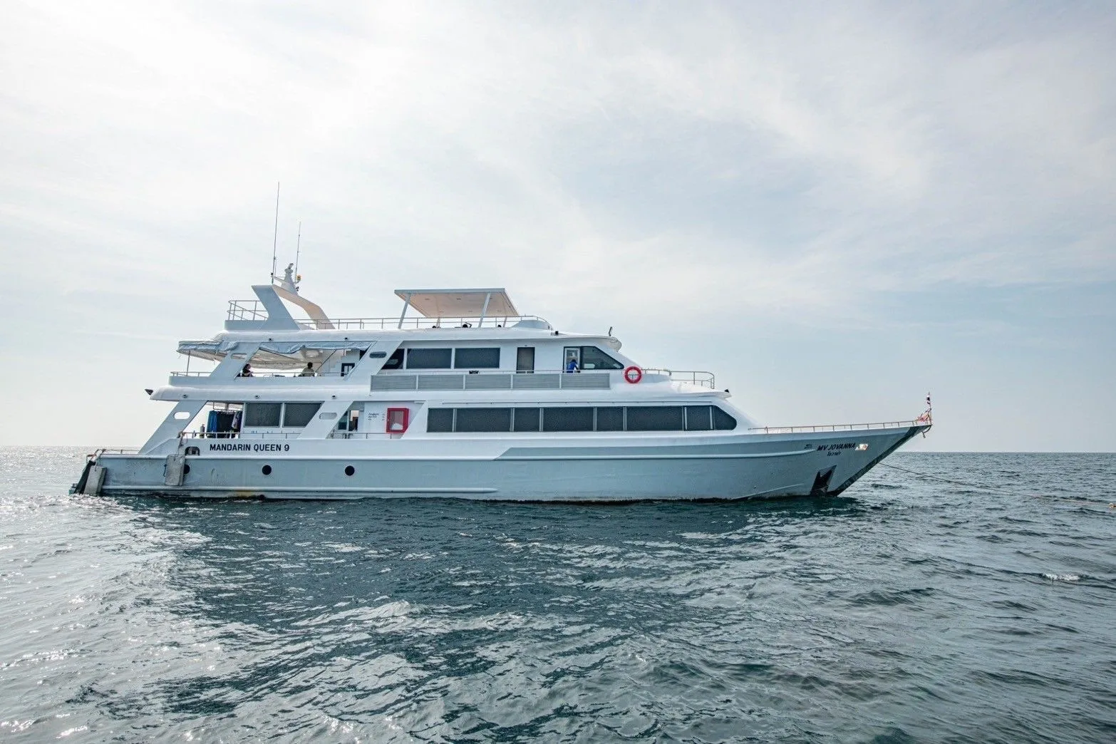 Mandarin Queen 9 in profile at anchor — white steel hull with her name on the side