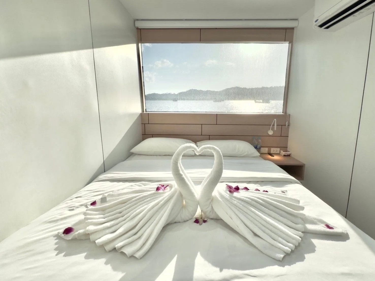 Swan-folded towels on a double bed by the window