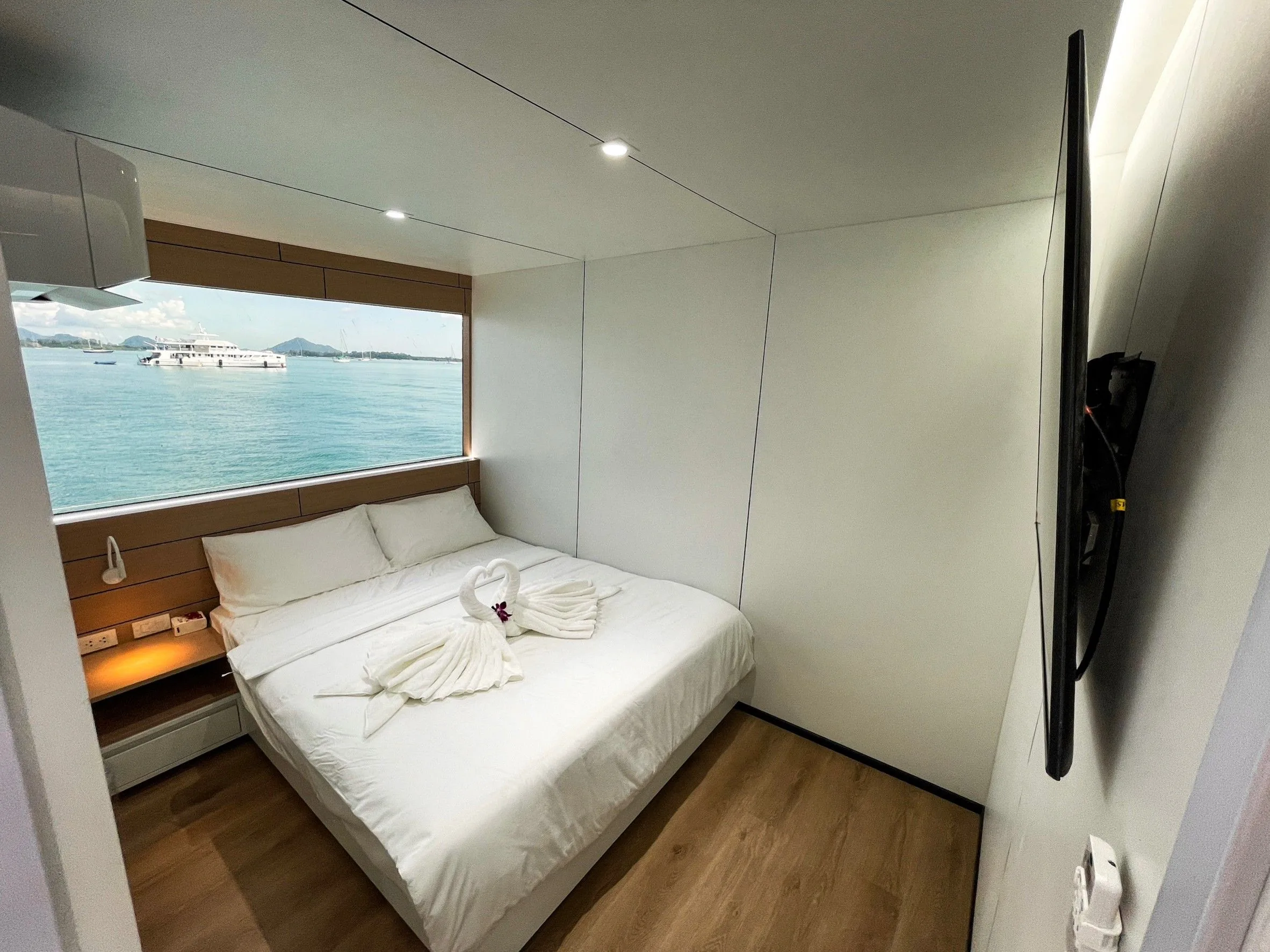 Cabin with a double bed, a TV and a view of the sea