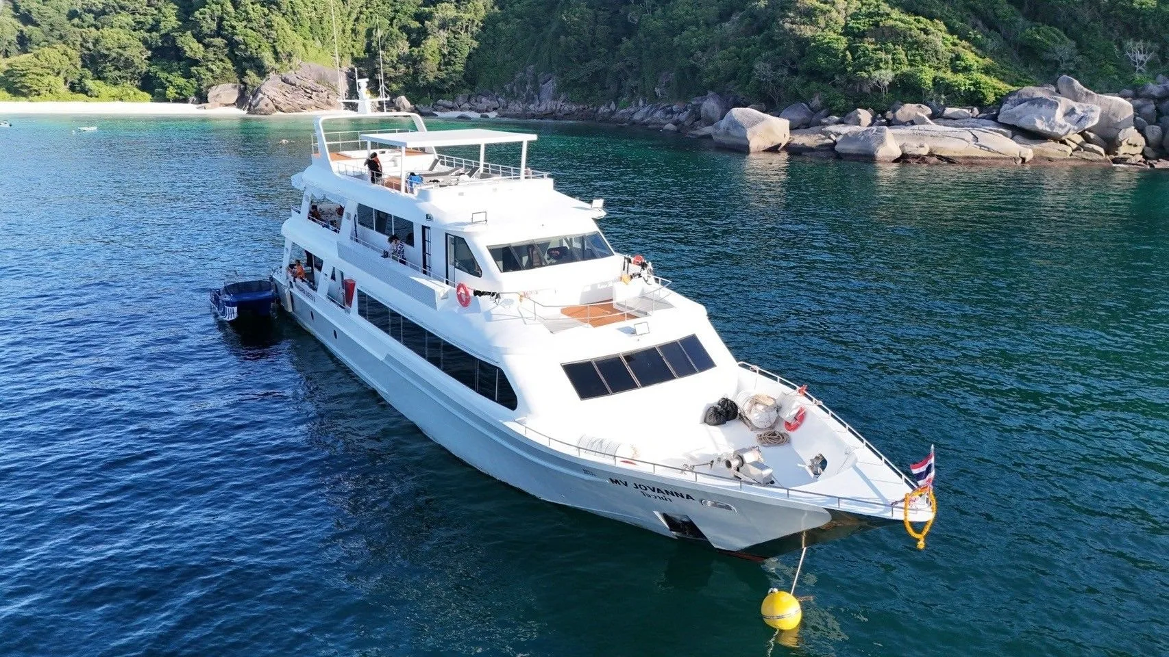 Mandarin Queen 9 off a Similan Islands beach, guests on the stern platform