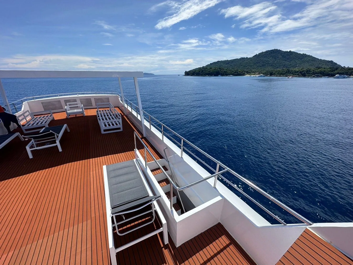 Teak sun deck with loungers and a view of the island
