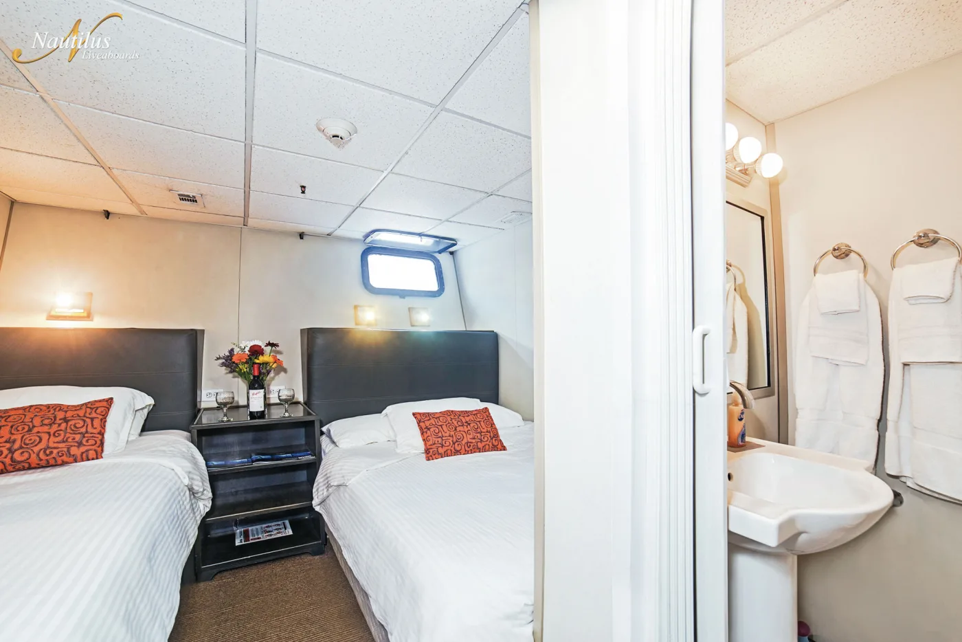 Stateroom на Nautilus Belle Amie — застеленные кровати и вход в санузел