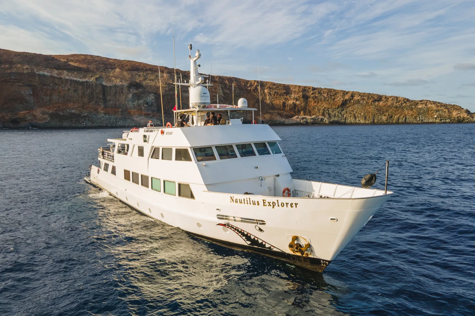 Nautilus Explorer носом к камере на фоне скалистого берега